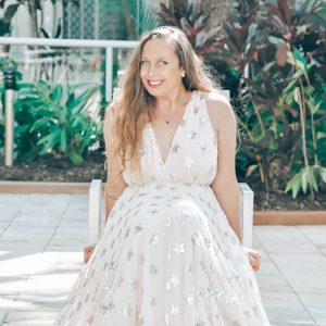 Emma Lovell sitting on a chair outside in Queensland wearing silver star dress shining with her personal brand