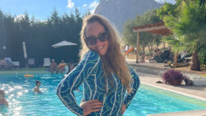 Do you live to work? Emma Lovell in a first nations bathing suit next to a pool in a sunny spot